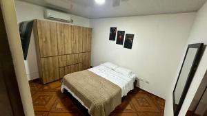 a small bedroom with a bed and a wooden cabinet at Casa comoda con aire y garaje en La Union Valle in Lemos