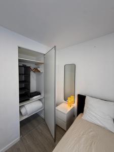 a white bedroom with a bed and a mirror at Une petite chambre cosy in Dijon