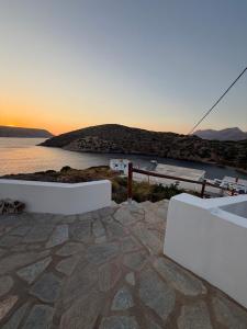 a sunset over a body of water with two white benches at PANDORA Φουρνοι Κορσεων in Nisída Foúrnoi