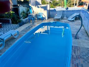 a blue swimming pool with a slide in a yard at Casa de Temporada de 1 Quarto com Piscina Gruta da Praia 2 in Saquarema