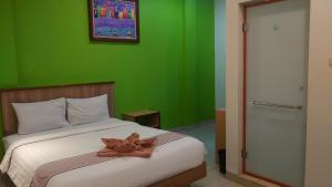 a green bedroom with a bed with a teddy bear on it at The Cabin Hotel Ngupasan in Yogyakarta