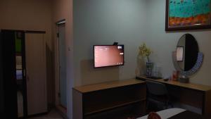 a room with a desk and a television on a wall at The Cabin Hotel Ngupasan in Yogyakarta