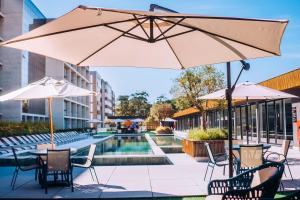 a patio with tables and chairs and an umbrella at Resort com Piscina Aquecida e Garagem em Xangri-lá in Xangri-lá +57 photos