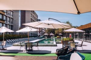a pool with tables and chairs and umbrellas at Resort com Piscina Aquecida e Garagem em Xangri-lá in Xangri-lá