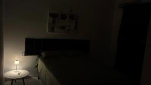 a dark bedroom with a bed and a table with a lamp at Pousada Apart Praia Uruaú in Beberibe