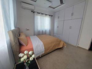 a bedroom with a bed and a vase of flowers at Monroe Luxury Apartments in Kumasi