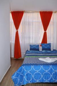a bedroom with a blue bed with red curtains at Hotel Inkanta in Ipiales