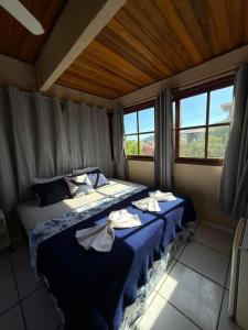 a bedroom with a blue bed with towels on it at Pousada Azul do Mar by BlueOcean in Arraial do Cabo