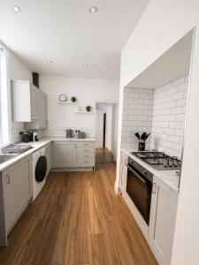 a kitchen with white appliances and a wooden floor at Queenie's Nook in North Shields