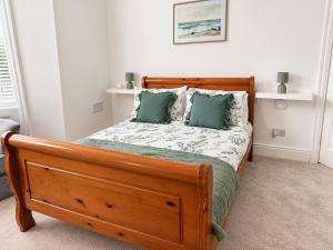 a bedroom with a wooden bed with two green pillows at Queenie's Nook in North Shields