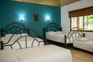 three beds in a room with blue walls at Hotel D'Lucia - Quebrada Ganado, Jaco, Costa Rica in Puntarenas