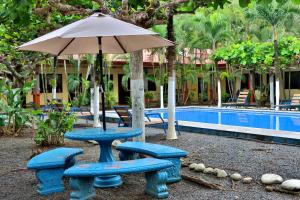 a table and chairs and an umbrella next to a pool at Hotel D'Lucia - Quebrada Ganado, Jaco, Costa Rica in Puntarenas