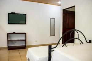 a room with a bed and a tv on the wall at Hotel D'Lucia - Quebrada Ganado, Jaco, Costa Rica in Puntarenas