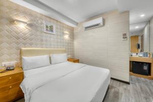 a bedroom with a large white bed and a kitchen at Suwara Hotel Kepong KL in Kuala Lumpur