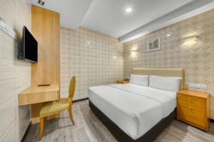 a bedroom with a bed and a desk and a tv at Suwara Hotel Kepong KL in Kuala Lumpur