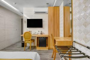 a room with a bed and a desk and a tv at Suwara Hotel Kepong KL in Kuala Lumpur