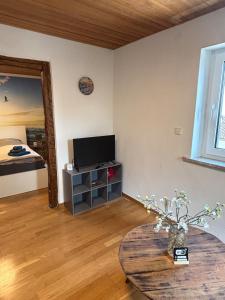 a living room with a table and a tv and a bed at Fewo kleine Auszeit in Karbach