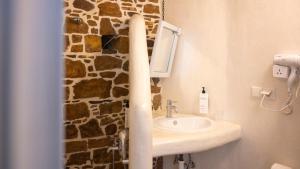 a bathroom with a sink and a stone wall at Rodakas Rooms-Dafni in LivadhokhÃ³rion +14 photos
