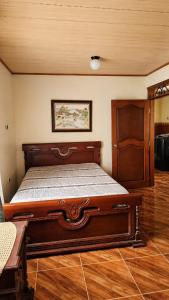 a bedroom with a large bed with a wooden frame at Casa campestre cerca de termales con WiFi y parqueadero in Santa Rosa de Cabal