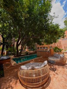 zwei große Korbstühle und -tische in einem Innenhof in der Unterkunft CIGNO Mejorada Hotel Boutique in Mérida