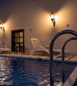 a swimming pool with two chairs and a light on the wall at Morea Kaleiçi-Adults Only in Antalya