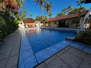 a swimming pool in front of a house at Chacara c piscina ampla em Pedro de toledo in Pedro de Toledo