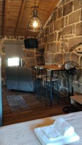 a table and chairs in a room with a stone wall at Fuinhas de Amor a 2 in Fuinhas