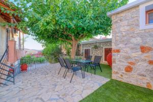 a patio with a table and chairs under a tree at Thymele Stone House in Lygourio +12 photos