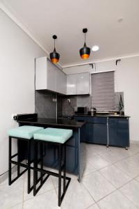 a kitchen with two stools and a black counter top at Luxury & modern 1 Bedroom apartments in Munyonyo-Kampala in Kampala