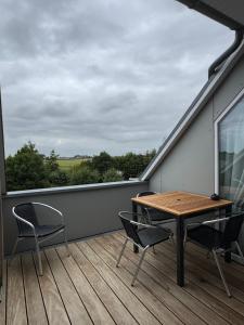 a balcony with a wooden table and chairs on a roof at Deichoase bei Friesens mit Sauna in Barsfleth