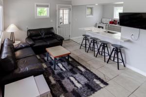 a living room with a leather couch and a kitchen at Westlake Cottage - Hillier Lodge in Wellington