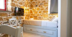 a stone walled bathroom with a bed and a mirror at Rodakas Rooms-Danae in LivadhokhÃ³rion +14 photos