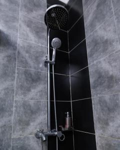 a shower with a black tile wall and a shower head at Luxury & modern 1 Bedroom apartments in Munyonyo-Kampala in Kampala