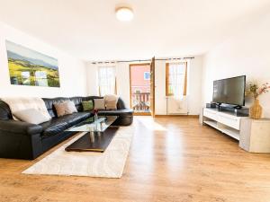 a living room with a black leather couch and a tv at KAISERLICH WOHNEN zentral und am Fluss in Bad Ischl
