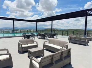 a patio with chairs and tables on a roof at Depa con alberca cerca de Andares y Landmark in Guadalajara