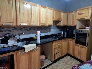 a kitchen with wooden cabinets and black counter tops at Centre boukidan in Al Hoceïma