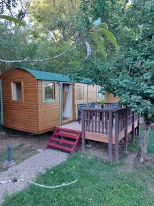 a wooden cabin with a table and a bench at La roulotte enchantée in Le Boissenet