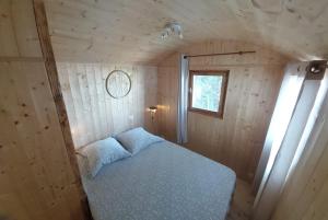 a small bedroom with a bed in a wooden room at La roulotte enchantée in Le Boissenet