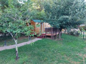 a log cabin in a yard with a tree at La roulotte enchantée in Le Boissenet