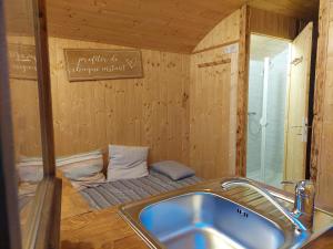 a bathroom with a sink and a small bed at La roulotte enchantée in Le Boissenet