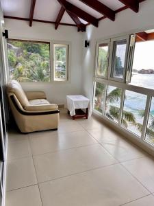a living room with windows and a couch and a table at Villa Chez Batista in Takamaka