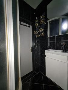 a black tiled bathroom with a white door and a sink at Apartman Ogulin "Klek Escape" in Sveti Petar