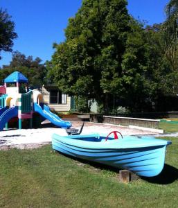 a blue boat sitting on the grass next to a playground at Edgewater Holiday Park in Port Macquarie