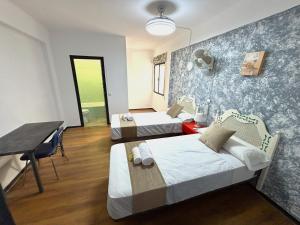 a room with two beds and a table and a desk at Evans Realty - Hostal in Fuengirola