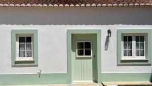 a white house with two windows and a door at Casa D'avó Souzinha in Ermidas