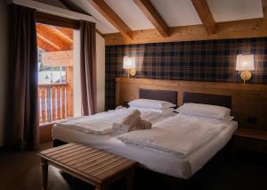 a bedroom with two beds and a table and a window at Hotel Orso Grigio in Selva di Cadore +105 photos