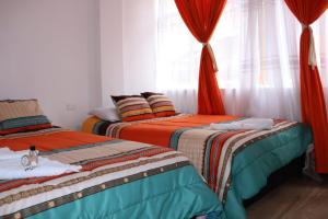 a room with two beds and a window with curtains at Hotel Inkanta in Ipiales