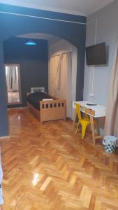 a living room with a wooden floor and a bed and a desk at Mora Hostel in Mendoza