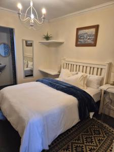 a bedroom with a large white bed and a chandelier at Fortune Cottage in Cape Town