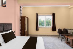 a bedroom with a bed and two chairs and a window at Hotel O Global Residency in Gurgaon